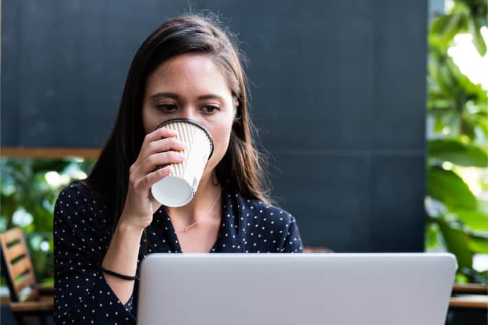 Femme buvant son café devant son ordinateur portable