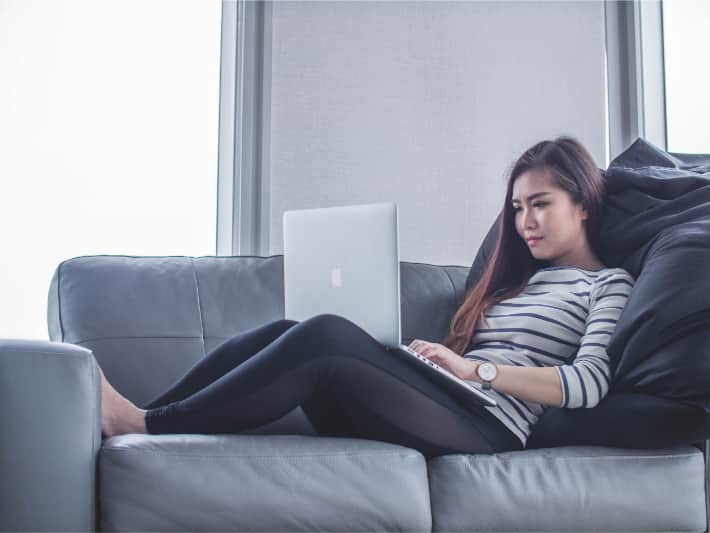 Femme allongée sur un canapé utilisant un ordinateur portable