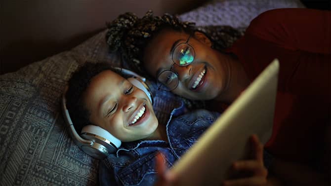 A mother and daughter look at a tablet. Setting up Apple iPad parental controls will help keep your child safe”